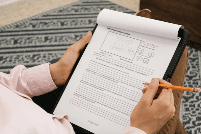 Persona llenando a mano el formato de genograma y dinámica familiar en una tablet